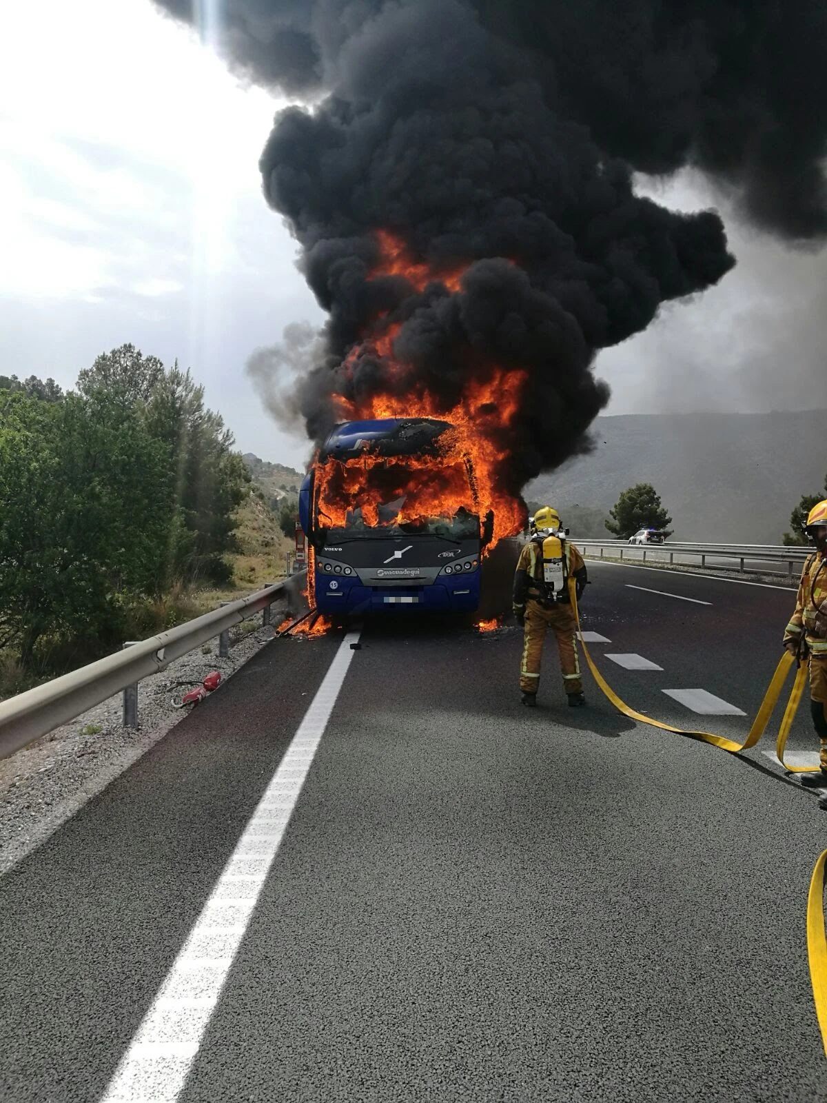 Un bombero frente a un autobús en llamas en la autovía